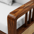 Wooden armrest of a sofa with a white cushion in the background