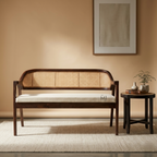 Wooden bench with woven backrest in a room with a beige wall and small table.
