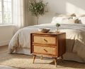 Modern solid wood bedside table with woven rattan drawers beside a contemporary bedroom bed
