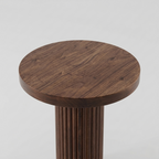 Wooden stool with a round top and cylindrical base on a light gray background