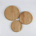 Three wooden coasters of different sizes on a light gray background