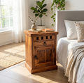 Rustic solid wood bedside table with drawer and cabinet storage beside a modern bed in walnut finish